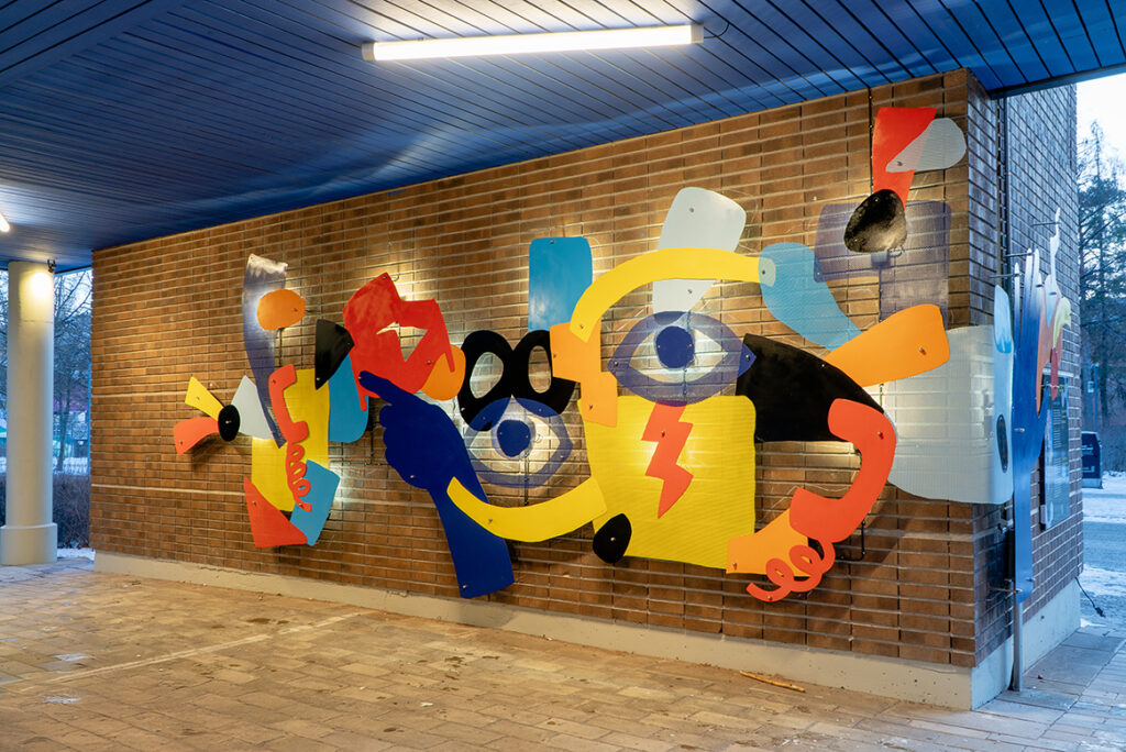 Colourful relief mural Samspel on a brick wall