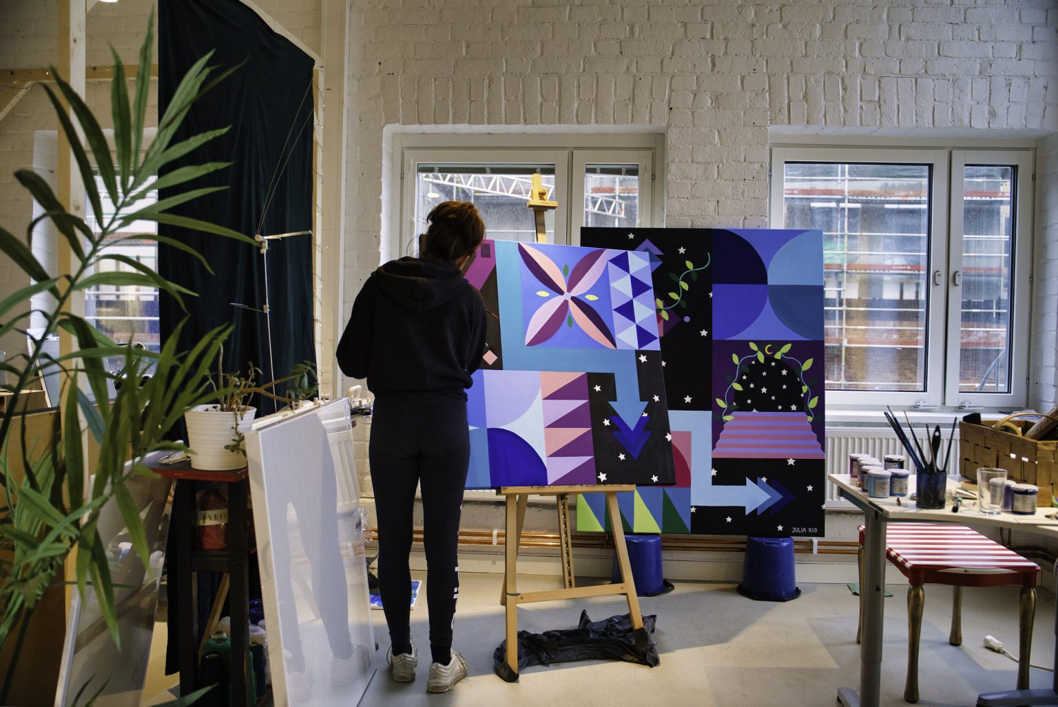 Artist working on a large colourful painting in the studio